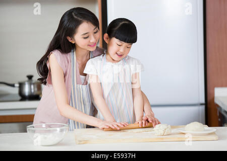 Happy mother and daughter rolling out dough Banque D'Images