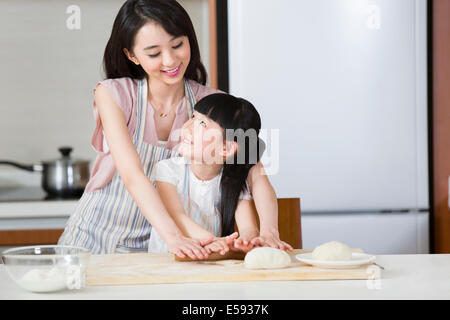 Happy mother and daughter rolling out dough Banque D'Images