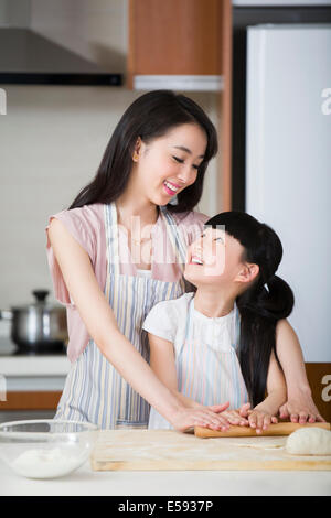 Happy mother and daughter rolling out dough Banque D'Images