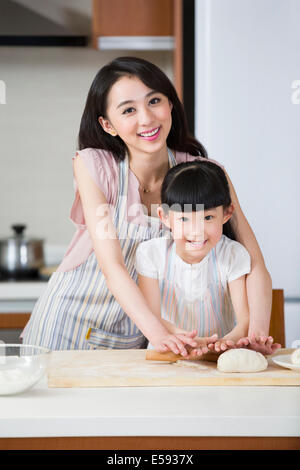 Happy mother and daughter rolling out dough Banque D'Images