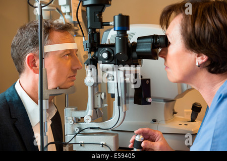 Femme optométriste examinant les yeux de l'homme Banque D'Images