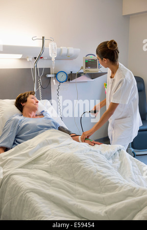 Infirmière Contrôle de pression artérielle du patient sur le lit d'hôpital Banque D'Images