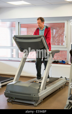 Homme qui court sur un tapis roulant dans une salle de sport Banque D'Images