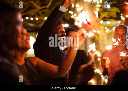 Amis jouant avec les étinceleurs at party Banque D'Images