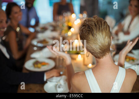 Woman clapping at dinner party Banque D'Images