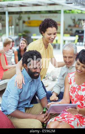 Des amis à l'aide de digital tablet at party Banque D'Images