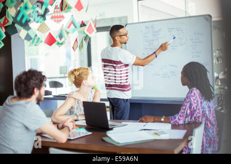 L'homme s'appuyant sur un tableau blanc pour les collègues Banque D'Images