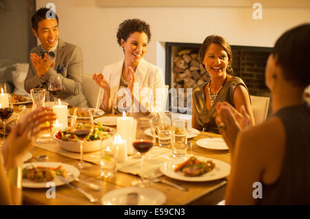 Les amis applaudir at dinner party Banque D'Images