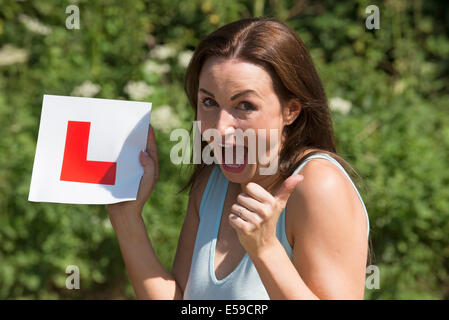 Portrait d'un pilote jubilant avec plaque après avoir passé l'examen de conduite. Donner un coup de pouce sign Banque D'Images