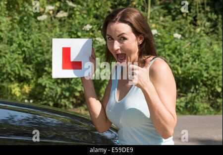 Portrait d'un pilote jubilant avec plaque après avoir passé l'examen de conduite. Donner un coup de pouce sign Banque D'Images