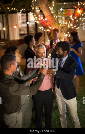 Les hommes toasting each other at party Banque D'Images