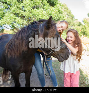 Mère et fille petting horse en plein air Banque D'Images
