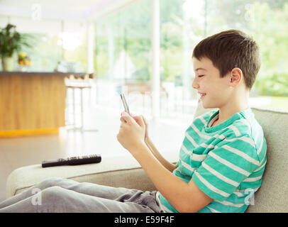 Boy using cell phone on sofa Banque D'Images