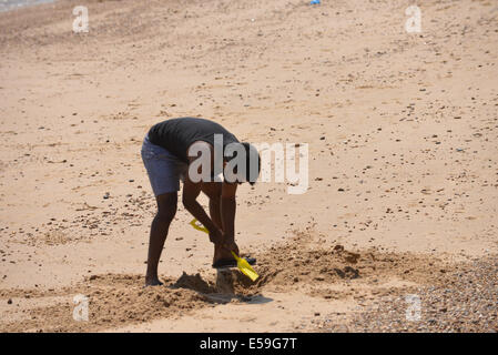 Clacton-on-Sea, Essex, Royaume-Uni. 24 juillet, 2014. Vous n'êtes jamais deux vieux pour creuser un trou sur la plage. La plage est pleine de gens profitant du beau temps sur une chaude journée à Clacton-on-Sea Crédit : Matthieu Chattle/Alamy Live News Banque D'Images