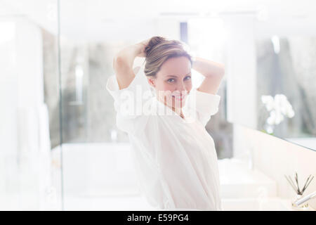 Woman putting up ses cheveux dans la salle de bains Banque D'Images