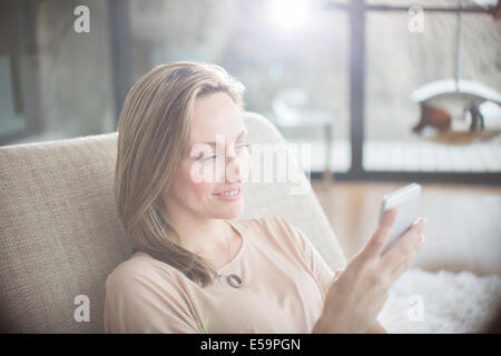 Woman using cell phone on sofa Banque D'Images