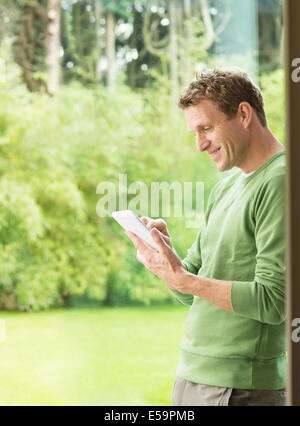 Man using digital tablet by window Banque D'Images