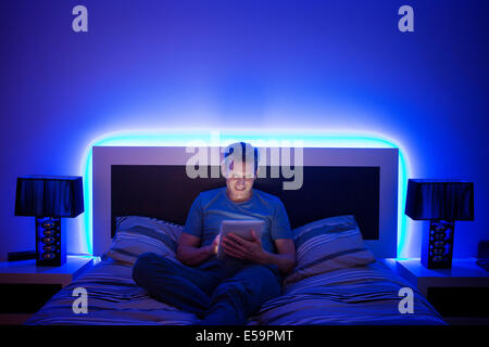 Man using digital tablet in bed Banque D'Images