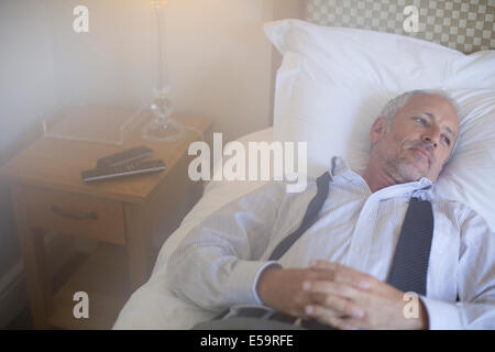 Businessman relaxing on bed in hotel room Banque D'Images