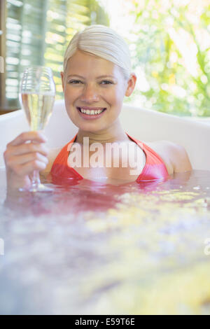 Femme buvant du vin blanc dans un bain à remous Banque D'Images