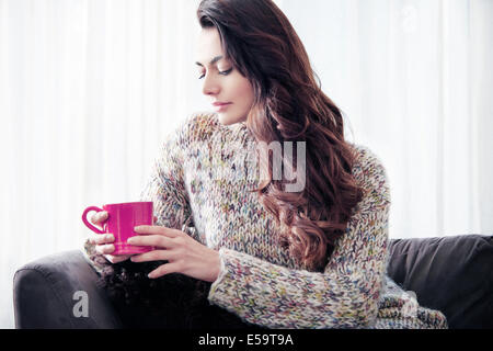 Femme buvant du café sur canapé Banque D'Images