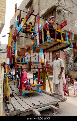 Les enfants sur une ancienne en bois merry-go-round à Karachi, Pakistan Banque D'Images