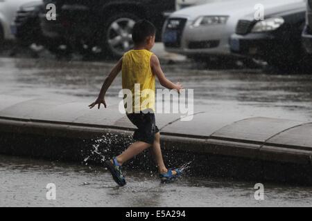 Qingdao, Chine, la province de Shandong. 24 juillet, 2014. Un jeune garçon s'exécute en pluie dans la ville de Qingdao, province de Shandong, Chine orientale, le 24 juillet 2014. Typhon Matmo apporté des pluies torrentielles dans la province. Credit : Wang Haibin/Xinhua/Alamy Live News Banque D'Images