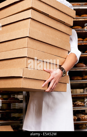 Hispanic Baker l'exercice pile de boîtes dans une boulangerie Banque D'Images