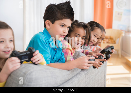 Enfants jouant à des jeux vidéo sur canapé Banque D'Images