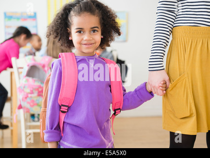 Student and teacher holding hands in classroom Banque D'Images