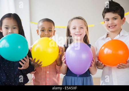 Enfants holding colorful balloons at party Banque D'Images