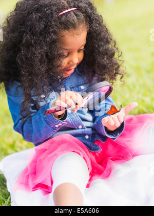 Mixed Race girl examinant papillon avec loupe Banque D'Images