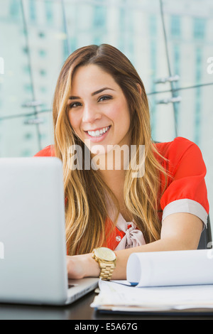 Mixed Race businesswoman smiling at desk Banque D'Images