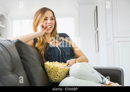 Mixed Race woman watching television on sofa Banque D'Images