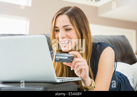 Mixed Race woman shopping online sur canapé Banque D'Images