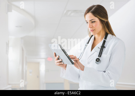 Mixed Race doctor using digital tablet in hospital Banque D'Images