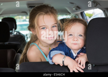 Portrait enfants assis sur la banquette arrière de la voiture Banque D'Images