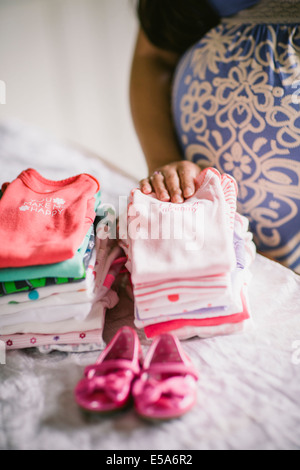 Pregnant Asian woman folding vêtements de bébé Banque D'Images