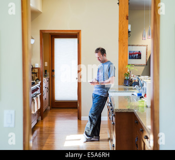 Man using cell phone in kitchen Banque D'Images