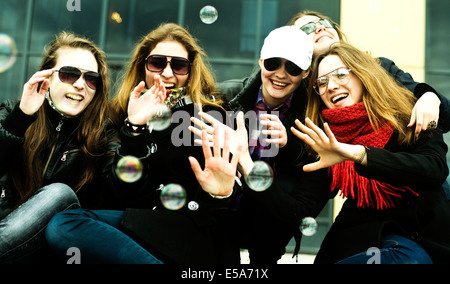 Femmes jouant avec des bulles on city street Banque D'Images