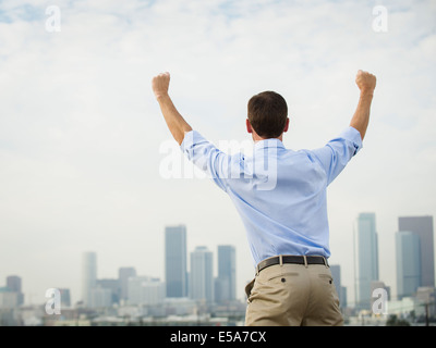 Caucasian businessman cheering on urban rooftop Banque D'Images