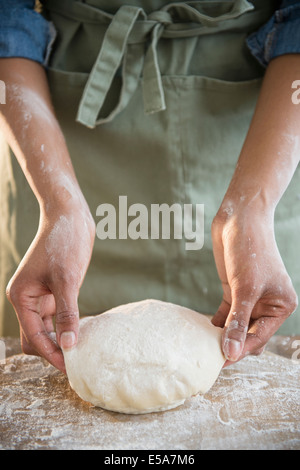 Mixed Race woman kneading dough Banque D'Images