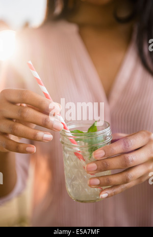 Mixed Race woman drinking cocktail Banque D'Images