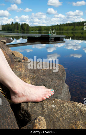 Les orteils au bord du lac des roches dans l'été en Finlande Banque D'Images