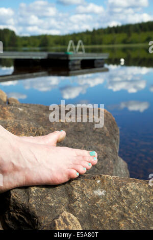 Les orteils au bord du lac des roches dans l'été en Finlande Banque D'Images