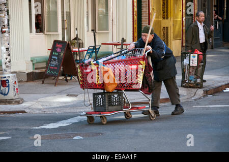 Homeless man pushing shopping trolley avec autrui par le lower Manhattan Banque D'Images