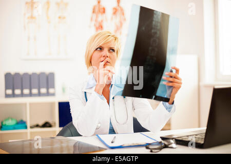 Femme médecin l'étude des rayons x de la colonne vertébrale, Debica, Pologne. Banque D'Images