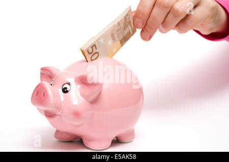 Coin bank rose cochon comme avec cinquante euro note dans une main féminine Banque D'Images