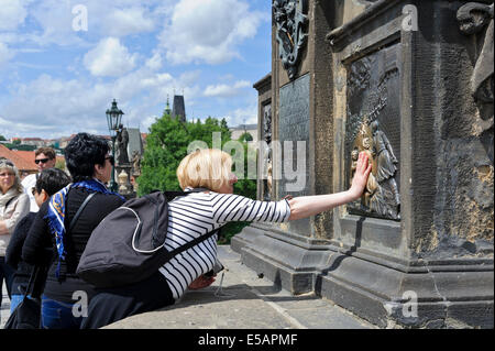 Toucher le bas-relief à la base de la statue de St Jean Napomuk sur le pont Charles, semble-t-il, apporte à la bonne chance, Prague. Banque D'Images