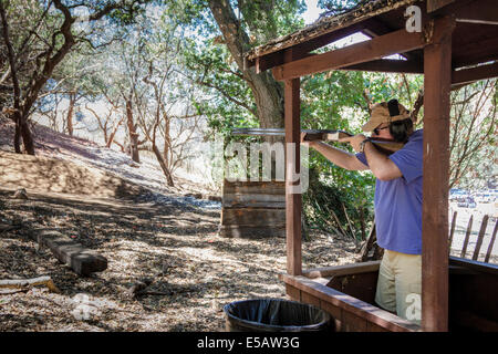 L'homme chasse tir avec son fusil sur un parcours dans les bois en Californie Banque D'Images